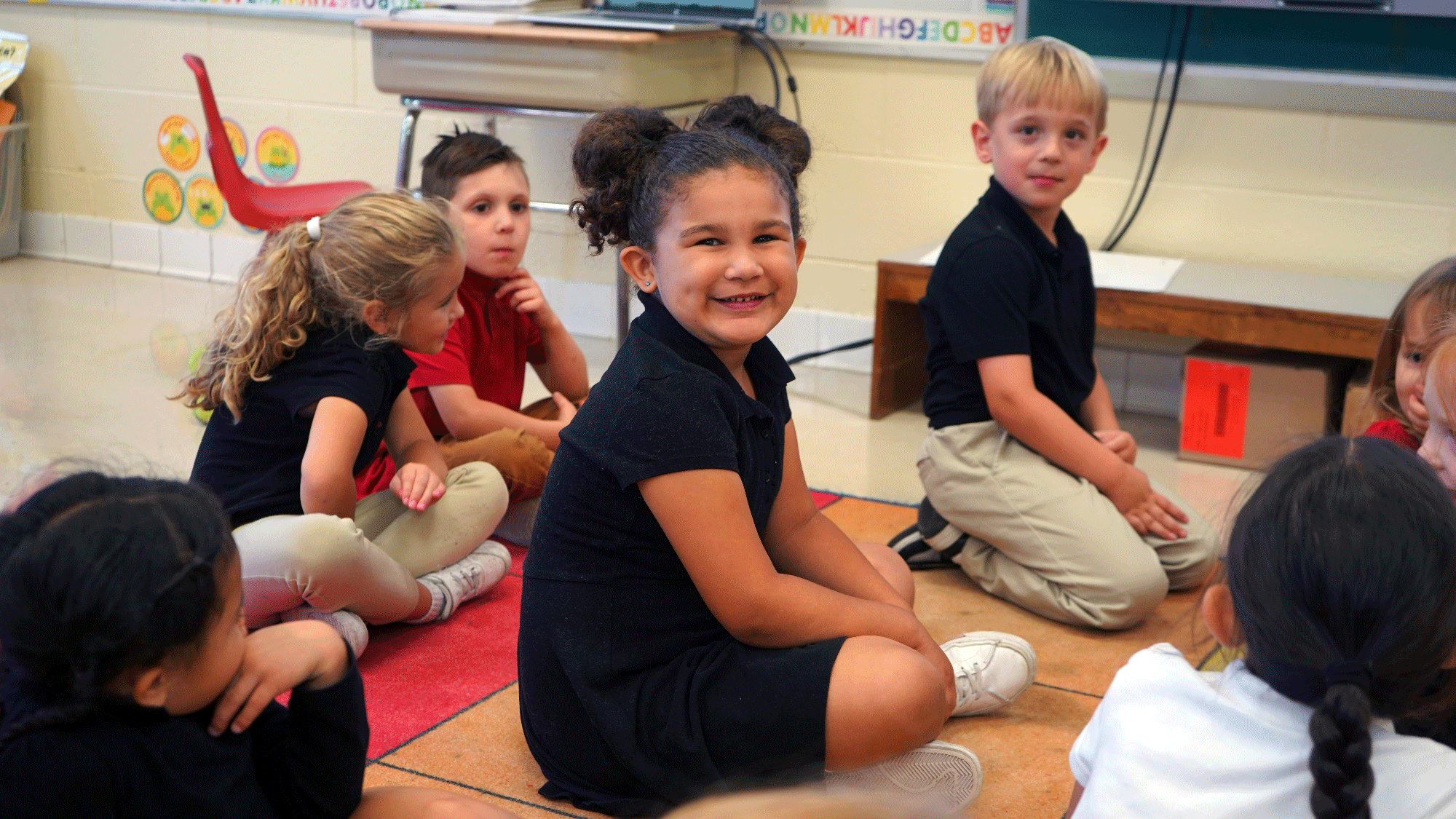 Students sitting together on a classroom rug.