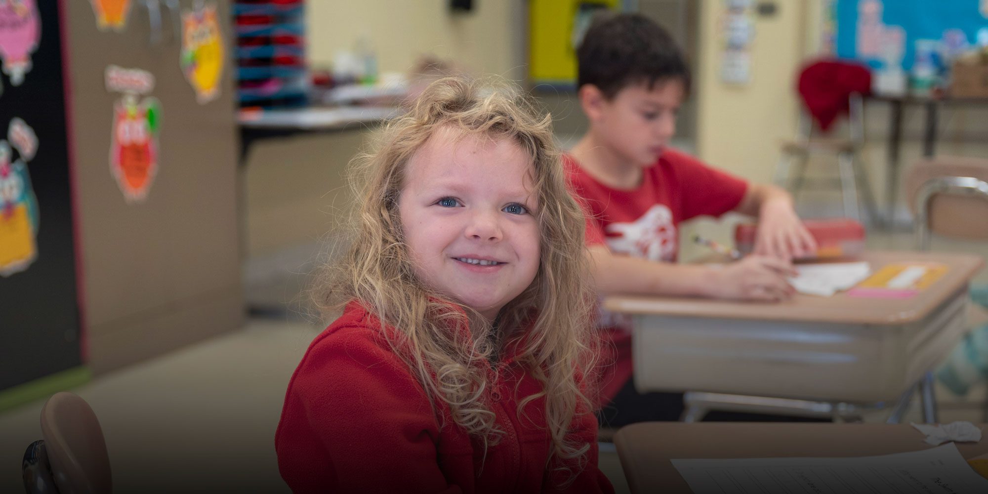Elementary student smiling and sitting in classroom